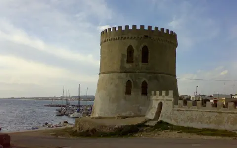Torre Vado centro storico: antica torre circolare con merlature, affacciata sul mare con barche ormeggiate.