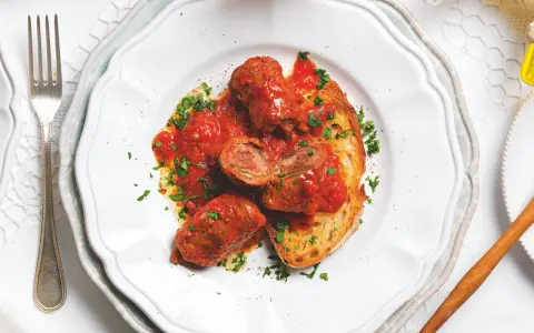 Braciole pugliesi in bianco, involtini di carne ripieni e cotti nel sugo, serviti su pane tostato e guarniti con prezzemolo fresco.