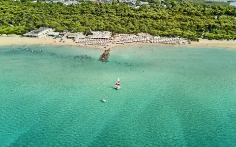 Spiaggia affollata con ombrelloni e mare cristallino a Marina di Ugento, dove si trova questo paradiso.