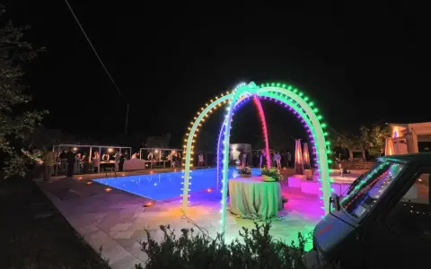 Serata magica con luci colorate, piscina illuminata e un'atmosfera da sagre di paese.