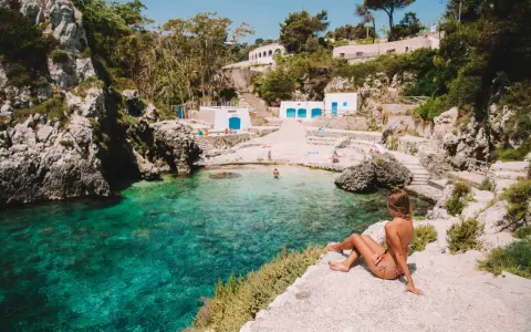 Una ragazza ammira la baia cristallina. Perfetto per decidere cosa fare stasera in Puglia: un tuffo rinfrescante!