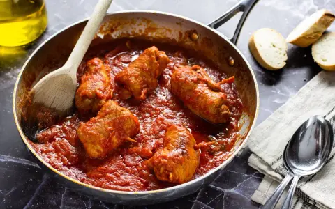 Braciola pugliese in padella con sugo rosso, pronte per essere gustate con pane fresco.