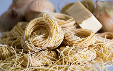 Nidi di pasta fresca, cipolle e un pezzo di formaggio, ingredienti perfetti per gustosi contorni pugliesi.