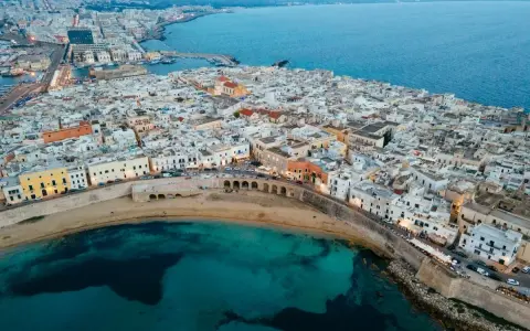 Vista aerea di Gallipoli, con le sue case bianche affacciate sul mare turchese. Immagina le feste estive e la vivacità di questa perla salentina.