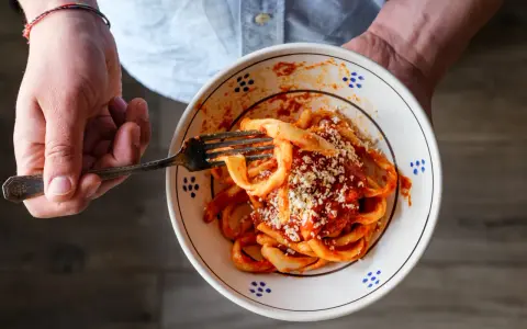 Un piatto di sagne al ragù, condite con formaggio grattugiato, pronto per essere gustato.