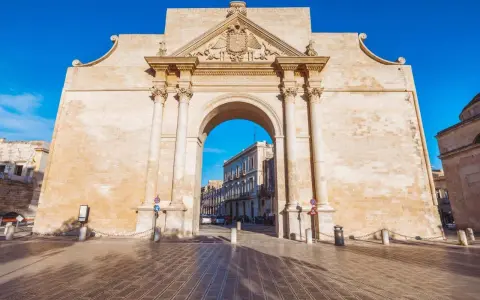 Porta Napoli, un arco trionfale in pietra leccese, invita a scoprire le cose da fare a Lecce. Un'antica porta che segna l'ingresso alla città barocca.