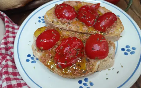Pane e pomodoro, un assaggio dei campi salentini. Bruschette condite con pomodorini freschi, olio d'oliva e origano, su un piatto decorato.