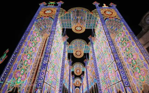 Un paese delle luminarie puglia incantato, con archi maestosi e decorazioni floreali di luci colorate che creano un tunnel magico nella notte.