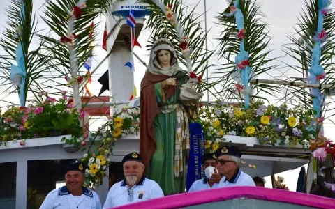Statua della Madonna su un peschereccio addobbato per la festa patronale di Santa Cesarea Terme, con marinai sorridenti.