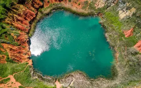 Laguna turchese in un cratere dalle rocce rosse, un paesaggio surreale delle cave di bauxite Otranto.