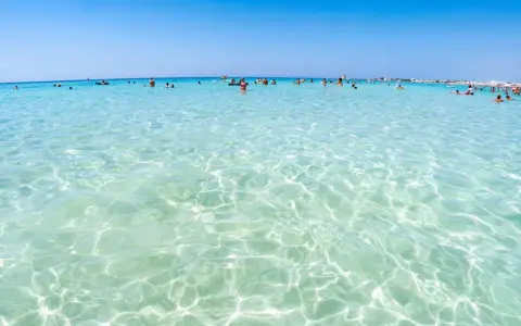 Acque cristalline e turchesi bagnano le spiagge di Lecce, dove bagnanti si godono il sole e il mare limpido.