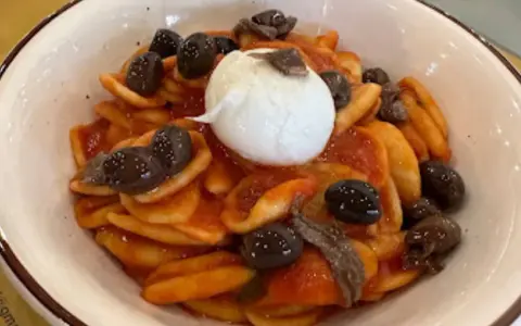 Orecchiette con pomodoro, olive nere, acciughe e burrata, un assaggio dei piatti tipici tarantini.