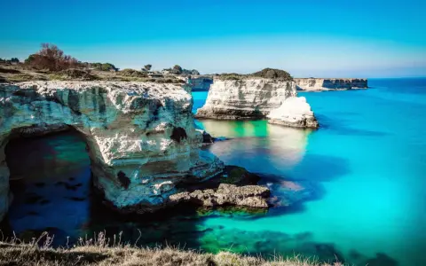 Scogliere bianche e mare turchese, un sogno per i mete puglia estate. L'arco naturale invita a scoprire le acque cristalline.