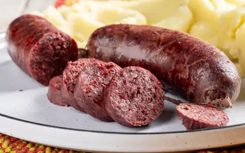 Sanguinaccio pugliese affettato e intero, servito con purè di patate. Un sapore autentico della tradizione.