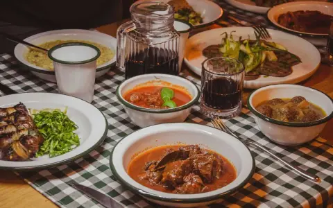 Tavola imbandita in una trattoria tipica salentina con vari piatti di carne e contorni, accompagnati da vino rosso.