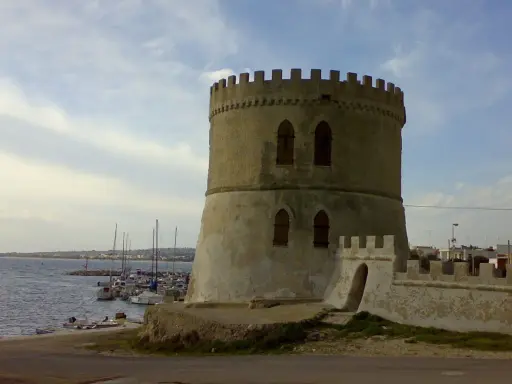 Torre Vado centro storico: antica torre circolare con merlature, affacciata sul mare con barche ormeggiate.