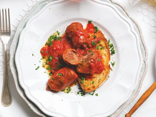 Braciole pugliesi in bianco, involtini di carne ripieni e cotti nel sugo, serviti su pane tostato e guarniti con prezzemolo fresco.
