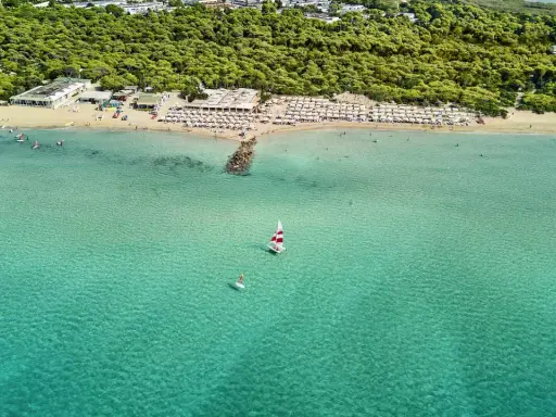 Spiaggia affollata con ombrelloni e mare cristallino a Marina di Ugento, dove si trova questo paradiso.
