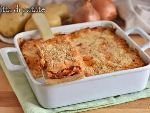 Una fetta di focaccia di patate ripiena pugliese dorata e croccante, servita da una teglia bianca.