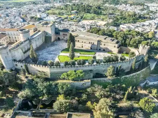 Castello normanno con torri rotonde e mura merlate, ideale per scoprire dove andare a Pasquetta in Puglia, circondato da verde e un borgo.