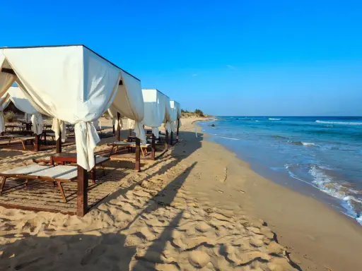 Spiaggia di Pescoluse con gazebo bianchi e lettini, mare azzurro e sabbia dorata. Ecco cosa vedere a Pescoluse per una vacanza da sogno.