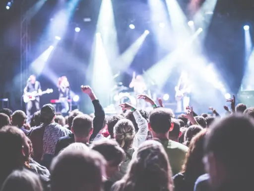 Folla entusiasta a un concerto in Puglia il 1 maggio, con luci intense e musicisti sul palco.