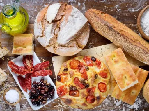Pane, focaccia, pomodori secchi e olive: un assaggio dei piatti tipici pugliesi, con olio d'oliva e sale.