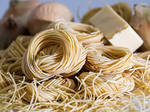 Nidi di pasta fresca, cipolle e un pezzo di formaggio, ingredienti perfetti per gustosi contorni pugliesi.