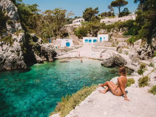 Una donna ammira il mare cristallino di una caletta pugliese. Perfetto per capire quando andare in Puglia per una vacanza indimenticabile.