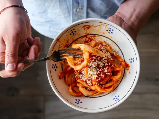 Un piatto di sagne al ragù, condite con formaggio grattugiato, pronto per essere gustato.