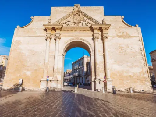 Porta Napoli, un arco trionfale in pietra leccese, invita a scoprire le cose da fare a Lecce. Un'antica porta che segna l'ingresso alla città barocca.