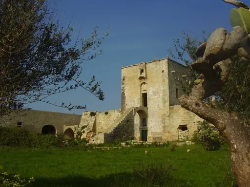 Antica masseria nella pianura salentina, con un torrione in pietra e vegetazione rigogliosa.