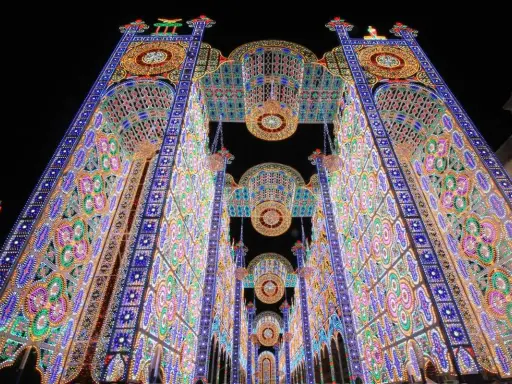 Un paese delle luminarie puglia incantato, con archi maestosi e decorazioni floreali di luci colorate che creano un tunnel magico nella notte.