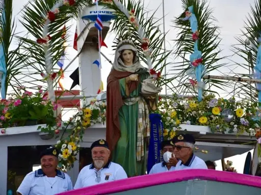 Statua della Madonna su un peschereccio addobbato per la festa patronale di Santa Cesarea Terme, con marinai sorridenti.