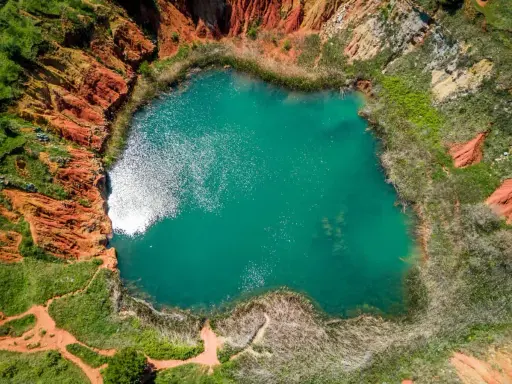 Laguna turchese in un cratere dalle rocce rosse, un paesaggio surreale delle cave di bauxite Otranto.