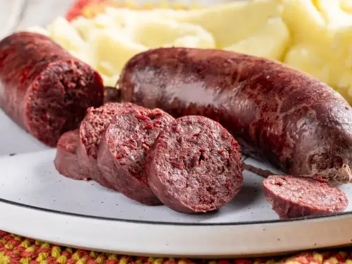 Sanguinaccio pugliese affettato e intero, servito con purè di patate. Un sapore autentico della tradizione.