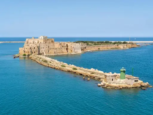 Fortezza Aragonese e faro verde a Brindisi, dove il mare azzurro incontra la storia.
