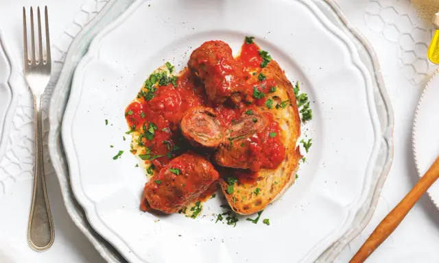 Braciole pugliesi in bianco, involtini di carne ripieni e cotti nel sugo, serviti su pane tostato e guarniti con prezzemolo fresco.