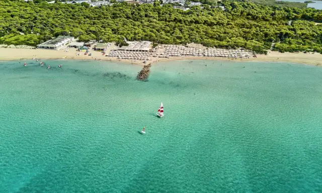 Spiaggia affollata con ombrelloni e mare cristallino a Marina di Ugento, dove si trova questo paradiso.