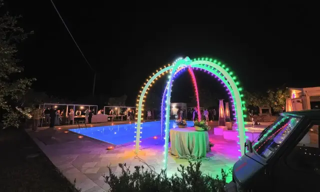 Serata magica con luci colorate, piscina illuminata e un'atmosfera da sagre di paese.