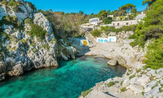 Baia incantevole con acque cristalline, perfetta per un tour Puglia 10 giorni. Case bianche e rocce a picco sul mare.