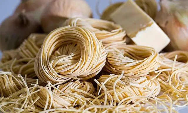 Nidi di pasta fresca, cipolle e un pezzo di formaggio, ingredienti perfetti per gustosi contorni pugliesi.