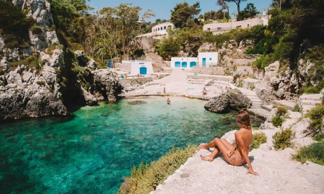 Una donna ammira il mare cristallino di una caletta pugliese. Perfetto per capire quando andare in Puglia per una vacanza indimenticabile.