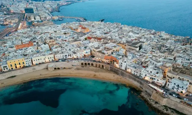 Vista aerea di Gallipoli, con le sue case bianche affacciate sul mare turchese. Immagina le feste estive e la vivacità di questa perla salentina.