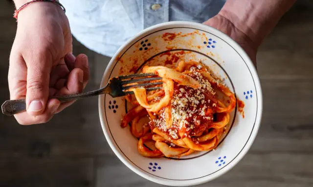 Un piatto di sagne al ragù, condite con formaggio grattugiato, pronto per essere gustato.