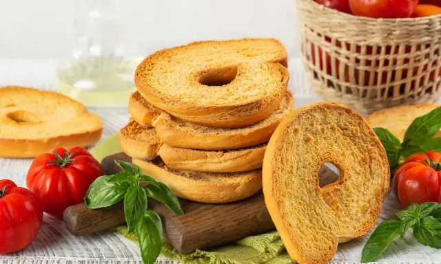 Fette dorate di pane tipico pugliese, con pomodori freschi e basilico, pronte per essere gustate.