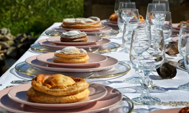 Tavola apparecchiata con bicchieri di cristallo e piatti rosa, su cui riposano dolci invitanti, tra cui una piscialetta leccese cosparsa di zucchero a velo.