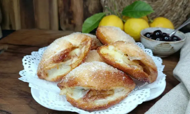 Monachine salentine dorate e zuccherate, un dolce profumato con ripieno di mele e un tocco di ciliegie.