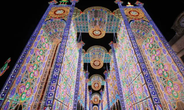 Un paese delle luminarie puglia incantato, con archi maestosi e decorazioni floreali di luci colorate che creano un tunnel magico nella notte.