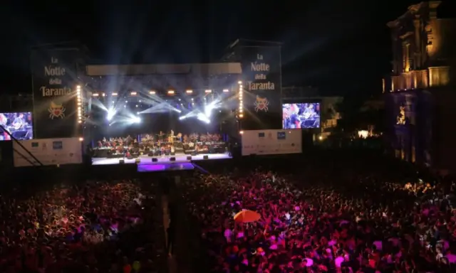 La Notte della Taranta, un'enorme folla festeggia sotto un palco illuminato. Le feste di settembre in Puglia sono magiche!